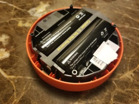a battery in an orange circular container