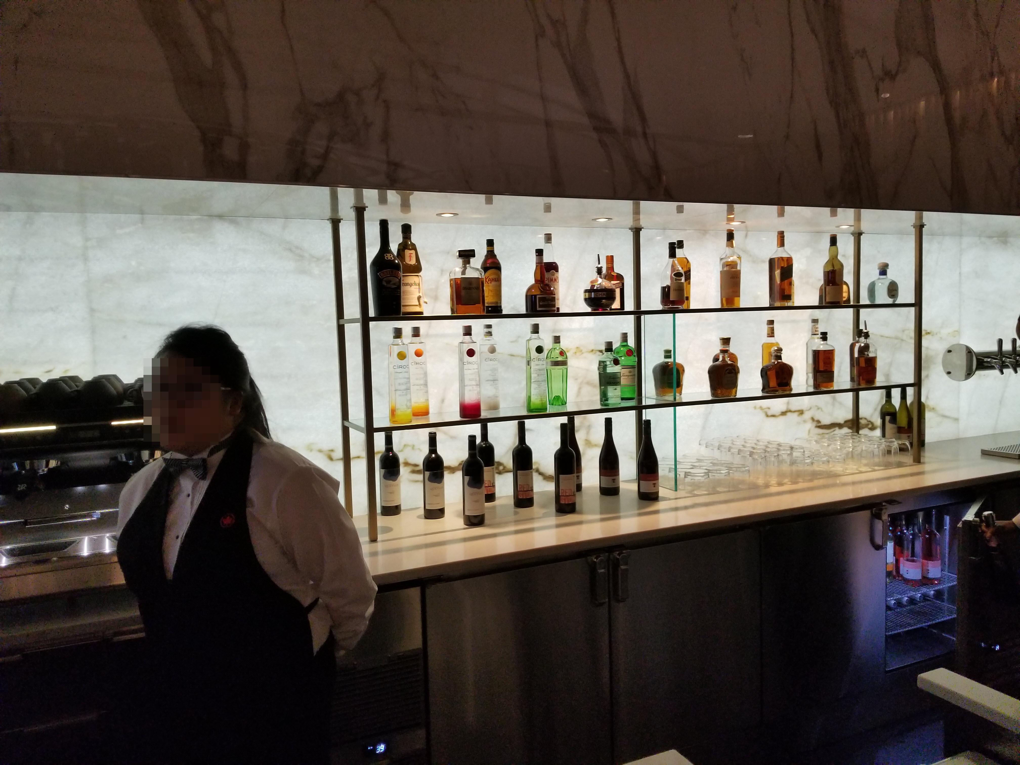 a woman standing behind a bar with bottles of alcohol