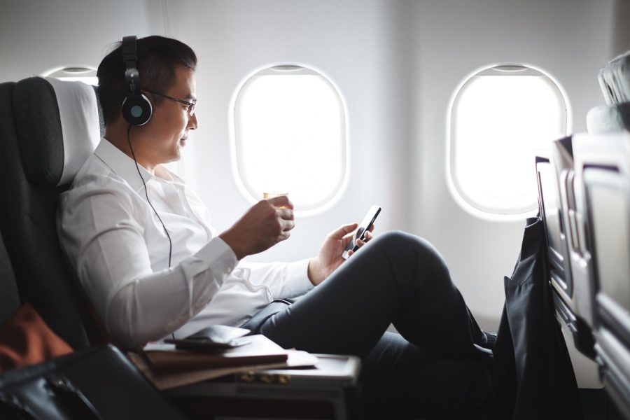 a man sitting in an airplane looking at a cellphone